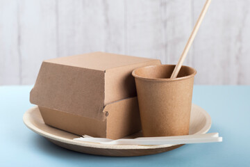 Biodegradable plate, cup, burger box and cutlery on light blue background. Recycling concept.