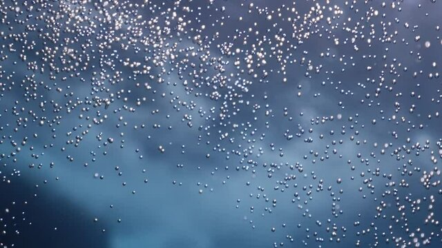 air bubbles underwater in blue water moving strange some in focus some out of focus making nive background shapes with sun rays and sun shine