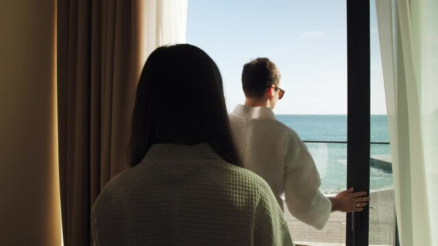 couple in hotel room by the sea, balcony offers sea and mountain views