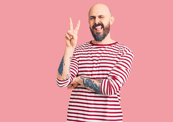 Fototapeta premium Young handsome man wearing casual clothes smiling with happy face winking at the camera doing victory sign. number two.