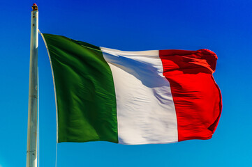 National flag of Italy waving in the wind over blue sky