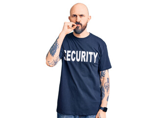 Young handsome man wearing security t shirt mouth and lips shut as zip with fingers. secret and silent, taboo talking