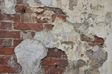 destroyed brick wall with fallen off plaster