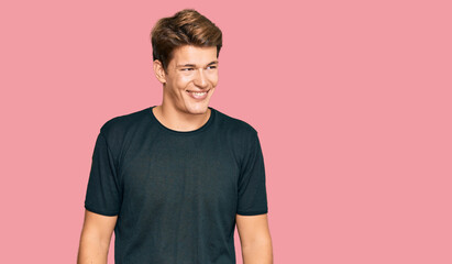 Obraz premium Handsome caucasian man wearing casual clothes looking away to side with smile on face, natural expression. laughing confident.