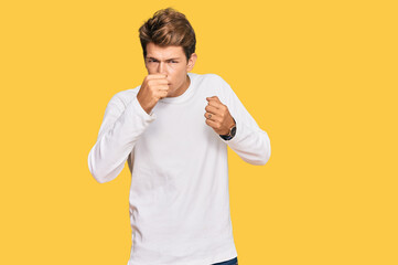 Handsome caucasian man wearing casual white sweater ready to fight with fist defense gesture, angry and upset face, afraid of problem