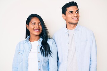 Fototapeta na wymiar Beautiful latin young couple wearing casual clothes looking away to side with smile on face, natural expression. laughing confident.