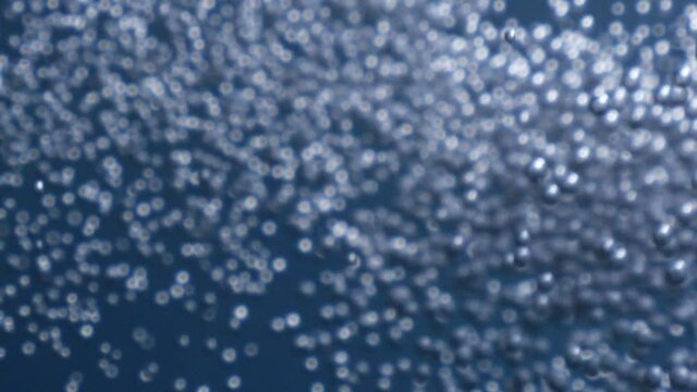 air bubbles underwater in blue water moving strange some in focus some out of focus making nive background shapes with sun rays and sun shine