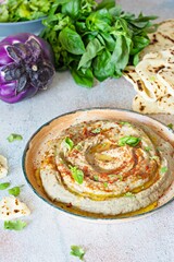 An oriental dish of baked eggplant babaganush (eggplant puree) with spices, herbs, lettuce and oriental flatbreads.