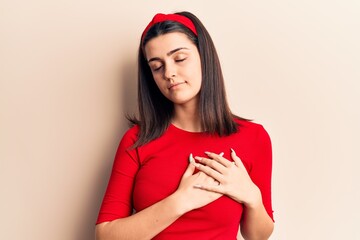 Young beautiful girl wearing casual t shirt and diadem smiling with hands on chest with closed eyes and grateful gesture on face. health concept.