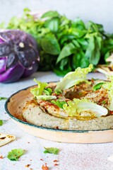 An oriental dish of baked eggplant babaganush (eggplant puree) with spices, herbs, lettuce and oriental flatbreads.