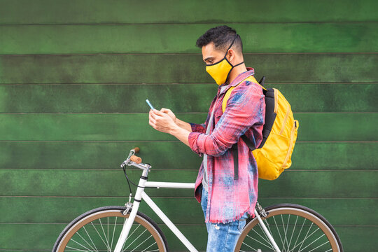 Latin American Young Man Wearing Mask And Using Phone Outdoors.