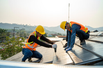 Roofer builder worker installing ceramic roof on top of the new roof at construction site.