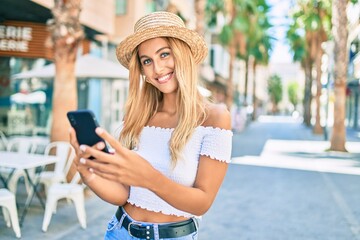 Young blonde tourist girl smiling happy using smartphone at the city.