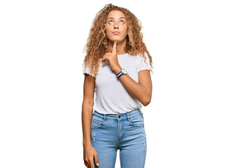Fototapeta premium Beautiful caucasian teenager girl wearing casual white tshirt thinking concentrated about doubt with finger on chin and looking up wondering