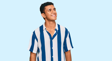 Young arab man wearing casual clothes looking away to side with smile on face, natural expression. laughing confident.