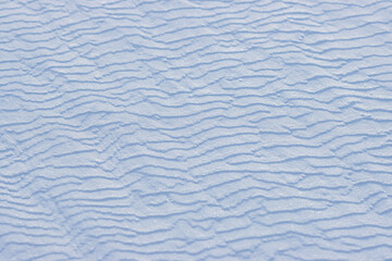 Beautiful winter background with snowy ground. Natural snow texture. Wind sculpted patterns on snow surface.