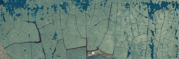 Peeling paint on the wall. Old concrete wall with cracked flaking paint. Weathered rough painted surface with patterns of cracks and peeling. Grunge texture for background and design. High resolution.