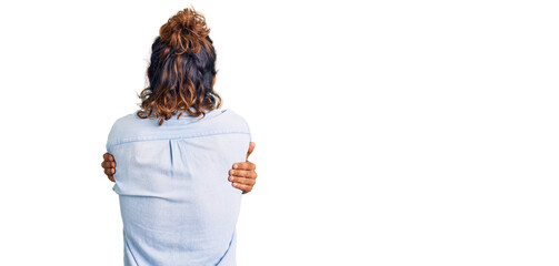 Young hispanic man wearing summer style hugging oneself happy and positive from backwards. self...