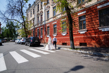 bride and groom in wedding dresses walking along the city streets on a wedding day