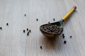 A handful of allspice in a wooden spoon.