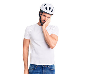 Young handsome man wearing bike helmet thinking looking tired and bored with depression problems with crossed arms.
