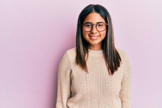 Young latin girl wearing casual winter sweater and glasses with a happy and cool smile on face. lucky person.