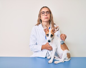 Young beautiful blonde veterinarian woman checking dog health using stethoscope depressed and worry for distress, crying angry and afraid. sad expression.