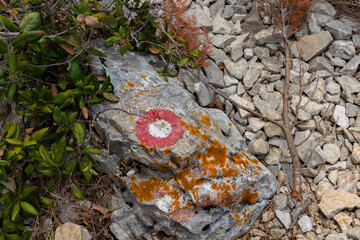 Red marking on the rock, signalization of path leading to the destination in the rough, dalmatian landscape of Hvar island, Croatia