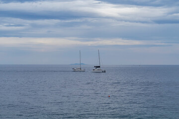 White sailboats sailing around Hvar island, popular nautical and tourist destination in the Dalmatian sea during cloudy day over sea