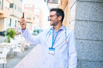 Young handsome hispanic doctor wearing uniform and stethoscope smiling happy Standing with smile on...