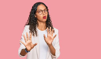 Young african american girl wearing business clothes moving away hands palms showing refusal and...