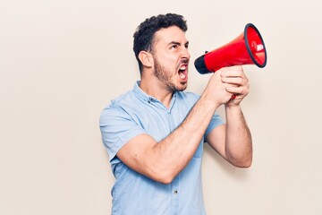 Young handsome hispanic man with angry expression. Screaming loud using megaphone standing over isolated white background