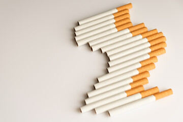Cigarettes with a yellow filter lie on a white surface