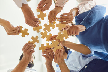 Fototapeta Positive company workers playing with jigsaw puzzle during team building activity obraz