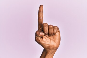 Arm and hand of black middle age woman over pink isolated background counting number one using index finger, showing idea and understanding