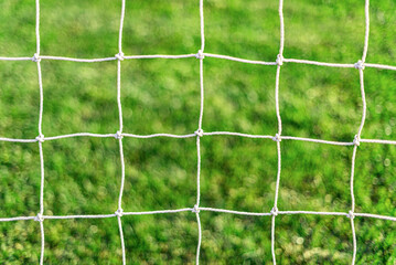 White soccer goal net on grass background close-up.