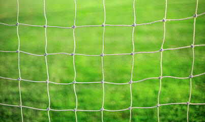 White soccer goal net on grass background close-up.