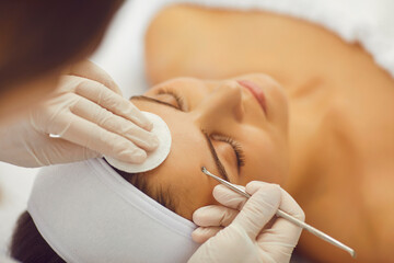 A beautician makes mechanical cleaning of a woman face in a cosmetic clinic. Cosmetologist making...