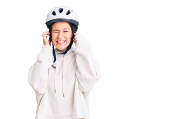Beautiful brunette young woman wearing bike helmet and sporty clothes covering ears with fingers with annoyed expression for the noise of loud music. deaf concept.