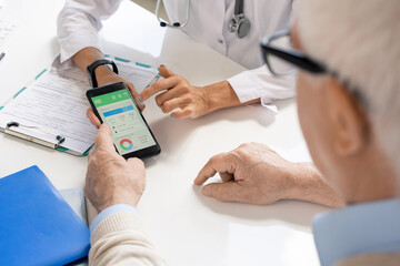 Hands of young female nutritionist showing her senior patient important data