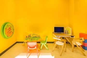 Bright yellow play space with little children's  colorful furniture and  toys