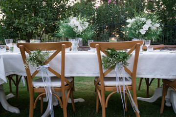 Fototapeta na wymiar Close-up of wedding chairs with decorated with white ribbons and flowers