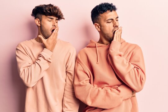 Young gay couple wearing casual clothes bored yawning tired covering mouth with hand. restless and sleepiness.