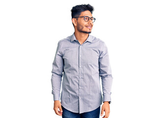 Handsome latin american young man wearing business clothes and glasses looking away to side with smile on face, natural expression. laughing confident.