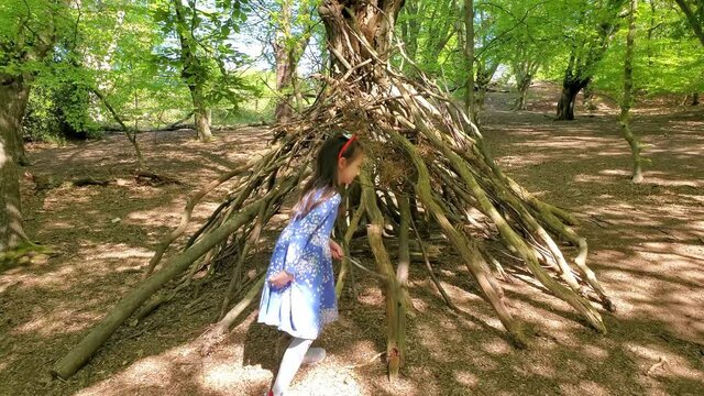 Little girl playing in the wickup, the hut made of btree brunches in Epping Forest, Loughton, London