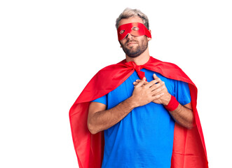Young blond man wearing super hero custome smiling with hands on chest with closed eyes and grateful gesture on face. health concept.