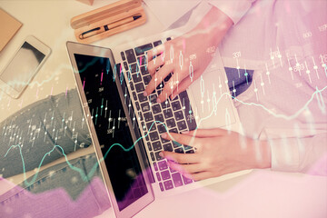 Double exposure of woman hands working on computer and forex graph hologram drawing. Top View....