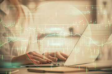 Double exposure of woman hands working on computer and forex graph hologram drawing. Financial analysis concept.