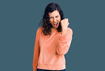 Young beautiful hispanic woman wearing casual clothes angry and mad raising fist frustrated and furious while shouting with anger. rage and aggressive concept.