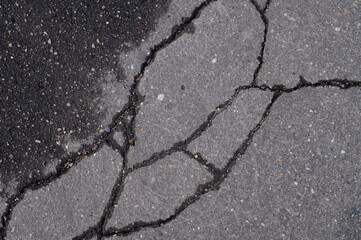 Abstract background of old cracked asphalt with wet traces of cars